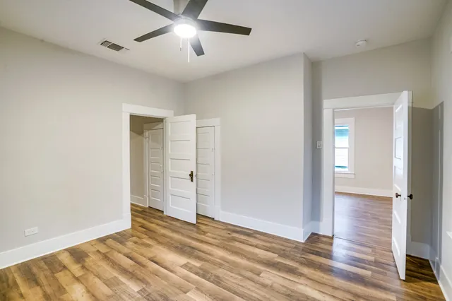 an empty room with wooden floor and ceiling fan