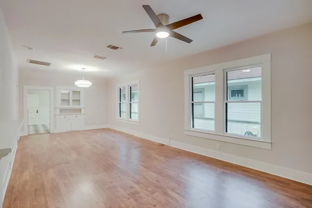 a view of empty room with wooden floor and fan