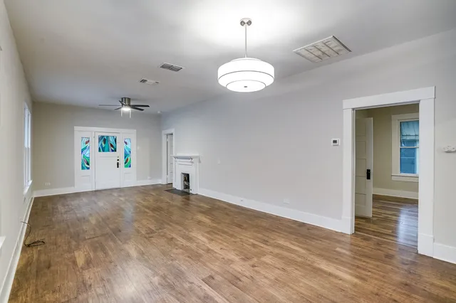 an empty room with wooden floor chandelier and windows