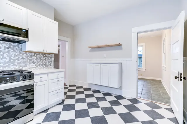 a kitchen with a checkered floor and white cabinets
