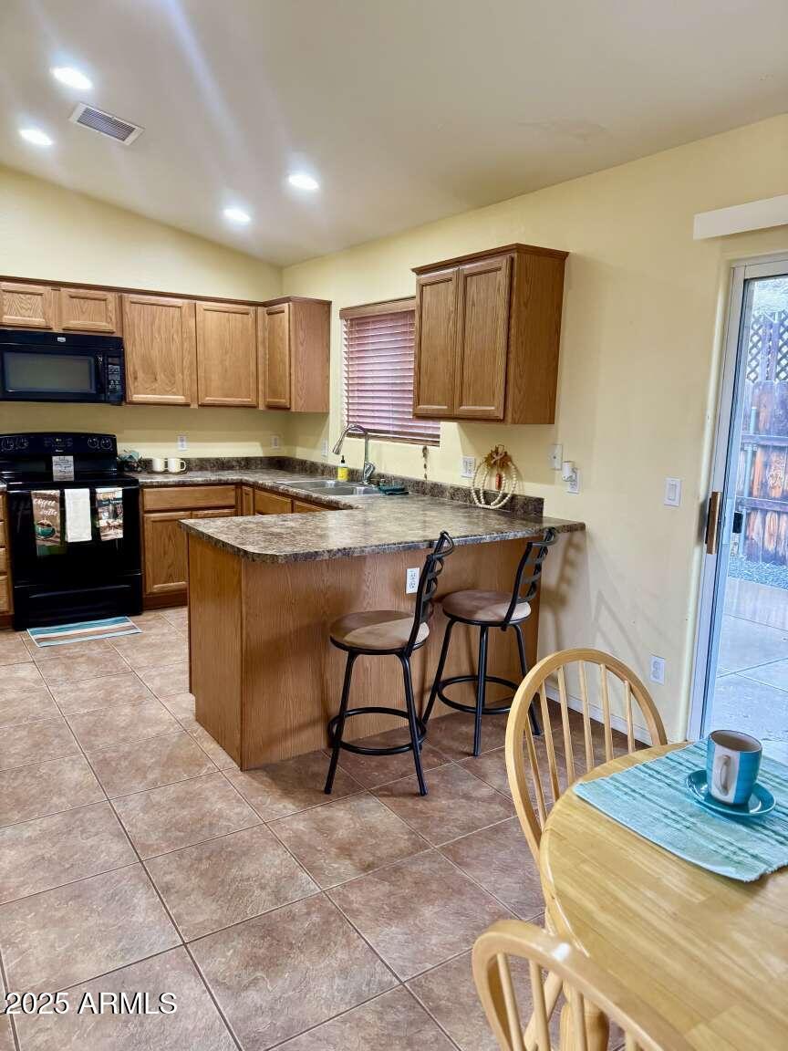 4660 Monument Way Rimrock, AZ 86335 - Photo 16 of 33 a kitchen with stainless steel appliances granite countertop a stove top oven a sink a dining table and chairs with wooden floor