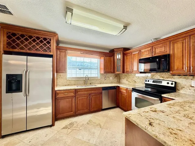 a kitchen with stainless steel appliances granite countertop a refrigerator a stove top oven a sink dishwasher and wooden cabinets