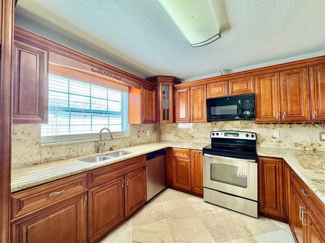 a kitchen with stainless steel appliances granite countertop a sink stove microwave and cabinets