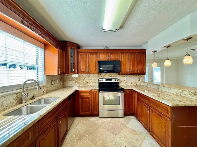 a kitchen with stainless steel appliances granite countertop wooden cabinets sink and stove top oven