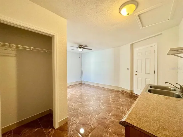 an empty room with wooden floor chandelier fan and windows