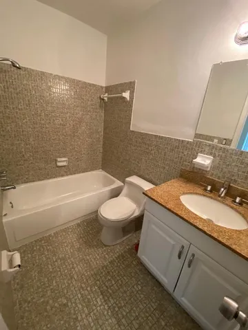 a bathroom with a granite countertop sink a toilet a mirror and bathtub