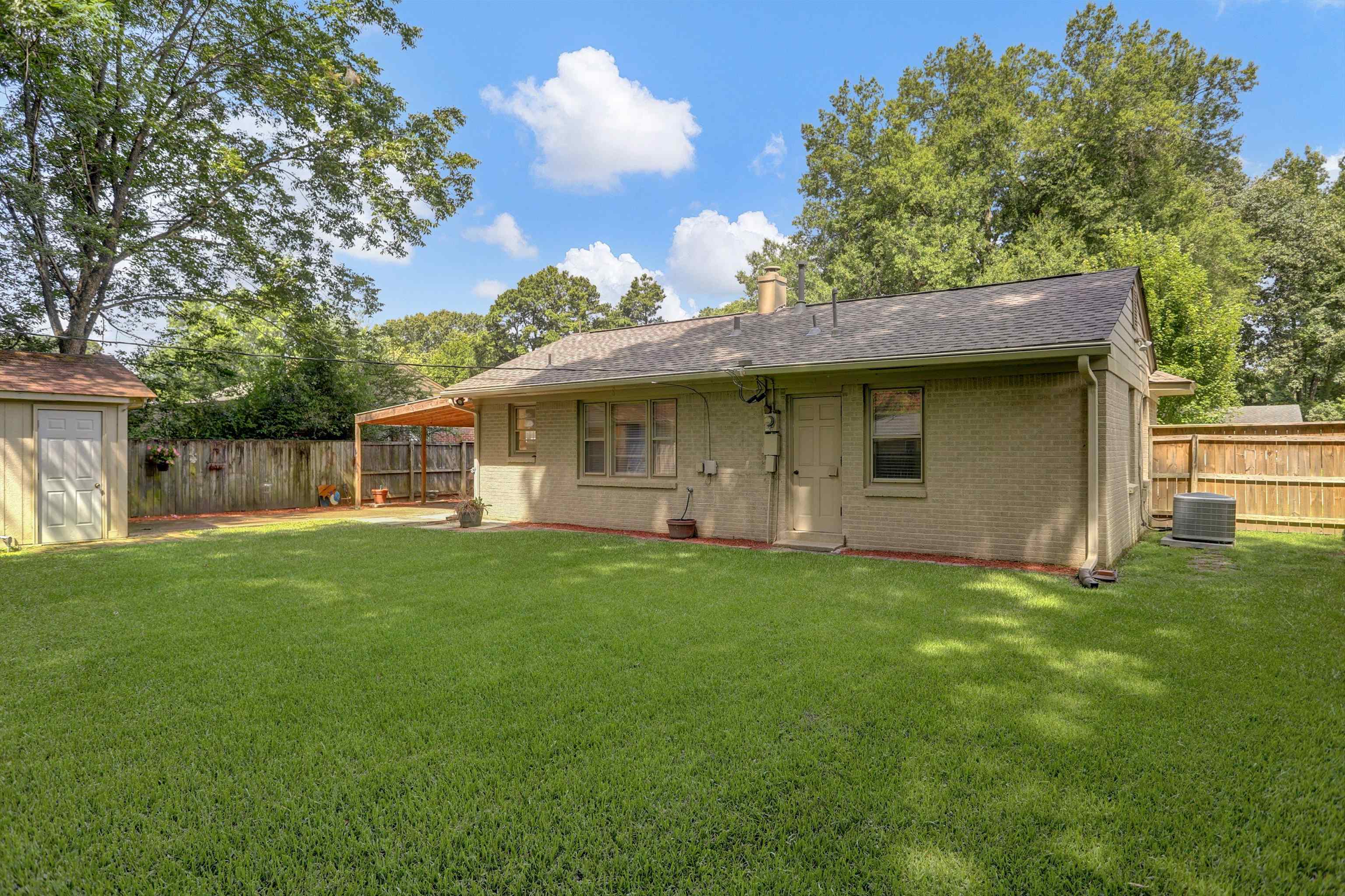 4545 Flamingo Road Memphis, TN 38117 - Photo 31 of 34 Spacious backyard featuring a brick exterior, a covered patio area, a detached storage shed, a wood privacy fence, and mature trees