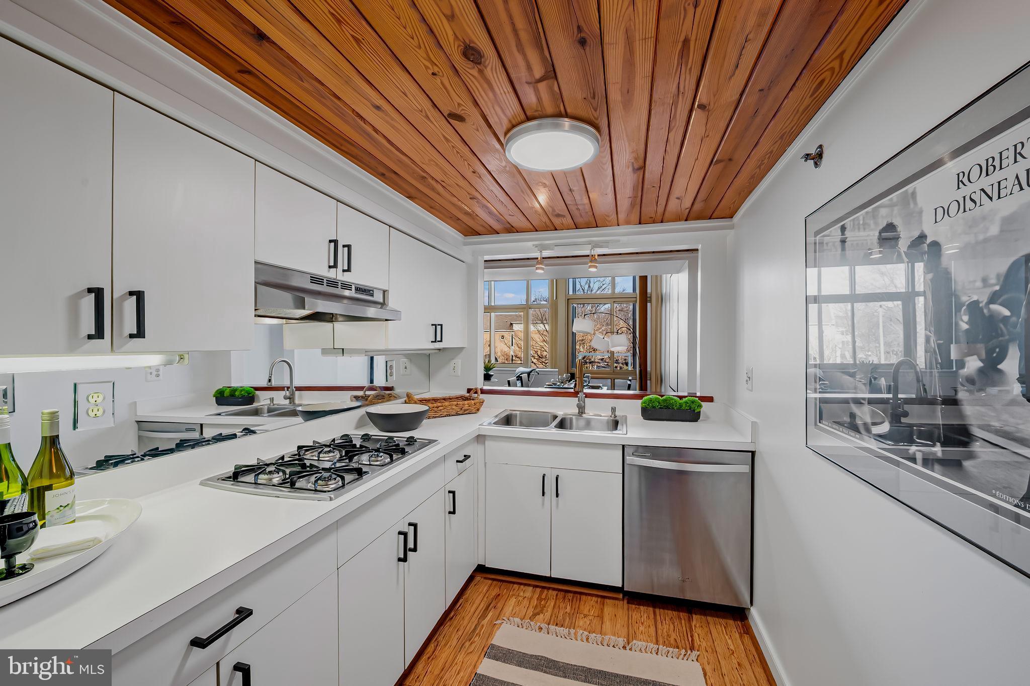 2901 Boston Street, Unit 204 Baltimore, MD 21224 - Photo 19 of 60 a kitchen with a sink a stove cabinets and a dining table chair