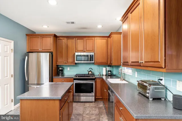 a kitchen with stainless steel appliances granite countertop a refrigerator a sink dishwasher a stove top oven a refrigerator and cabinets