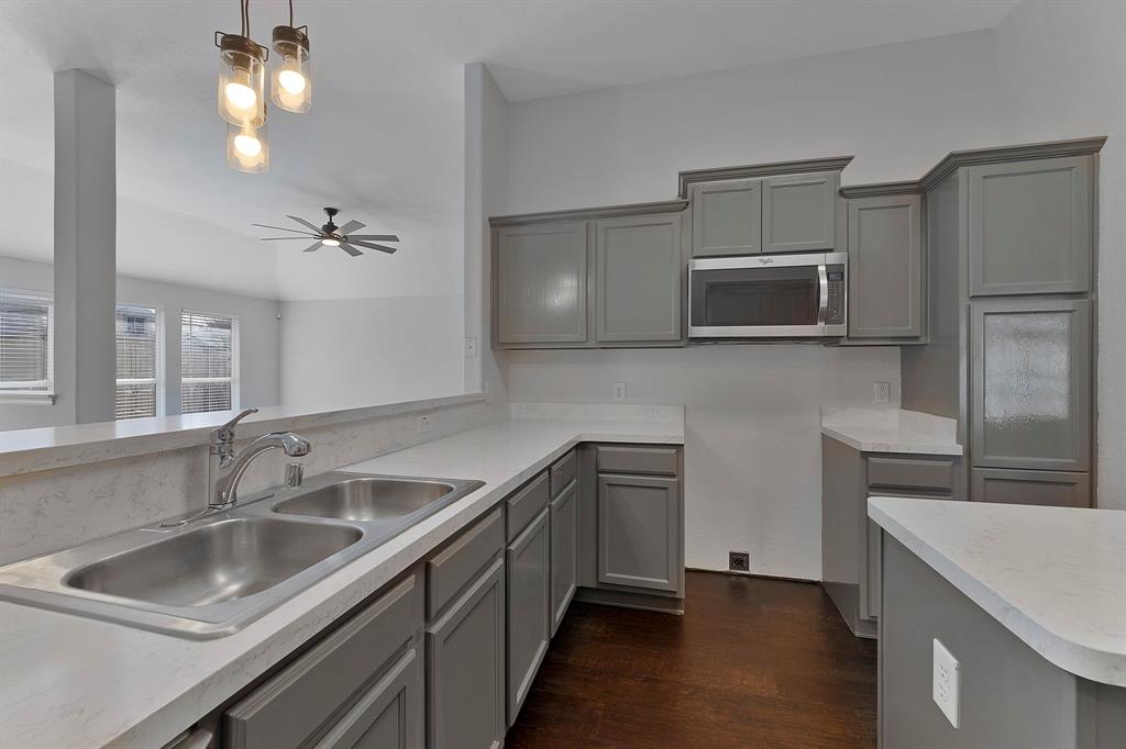 605 Clearbrook Street Azle, TX 76020 - Photo 10 of 33 Kitchen featuring gray shaker-style cabinetry, light-toned countertops, and a double basin stainless steel sink with a chrome faucet