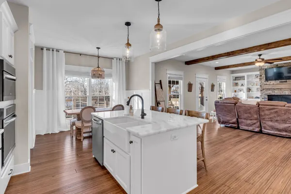 a large kitchen with stainless steel appliances kitchen island granite countertop a table chairs in it and a wooden floors