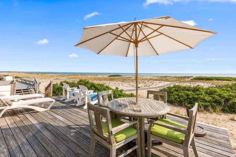 596 Shore Road, Unit 3 Truro, MA 02666 - Photo 9 of 37 a view of a balcony with table and chairs under an umbrella
