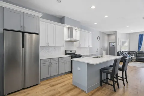a kitchen with stainless steel appliances granite countertop a table chairs sink refrigerator and cabinets