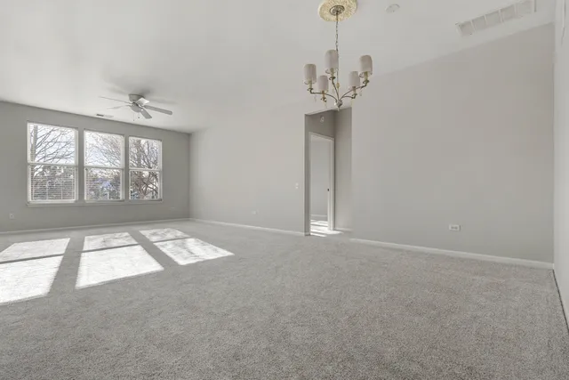 en empty room with windows and chandelier