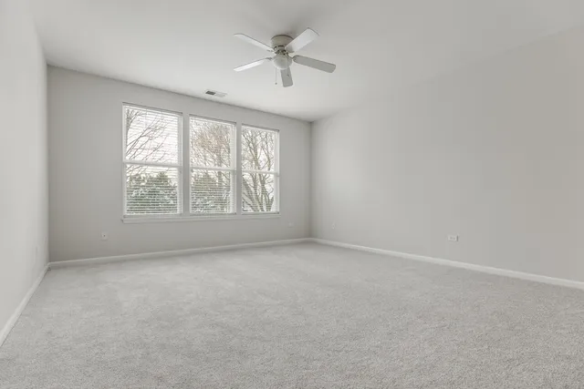 an empty room with a window and a ceiling fan