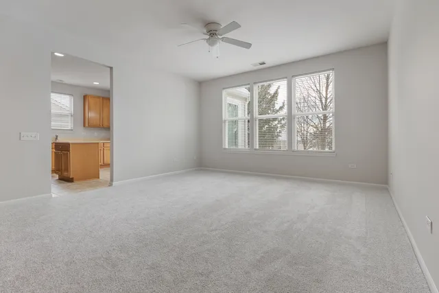an empty room with chandelier fan and windows