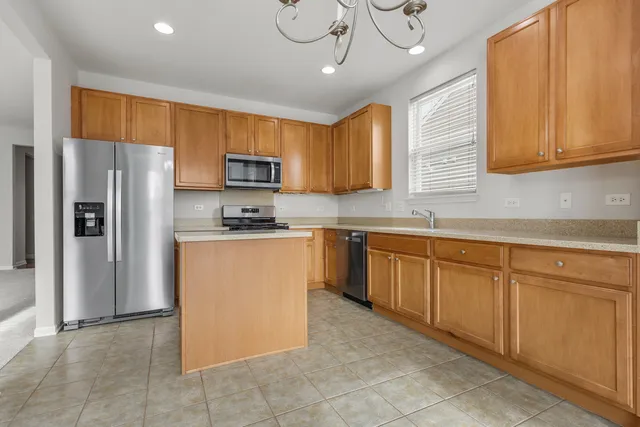 a kitchen with stainless steel appliances granite countertop a refrigerator a sink dishwasher a stove with wooden cabinets and a granite countertops