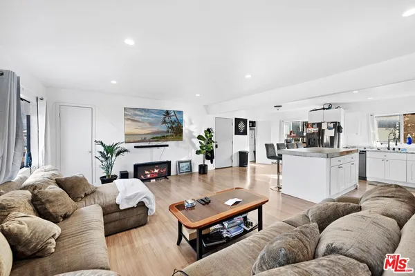 a living room with furniture kitchen view and a large window