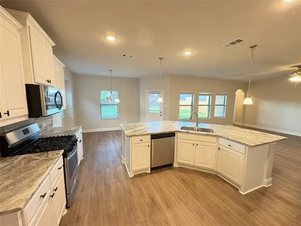 a kitchen with a sink stove and wooden floor