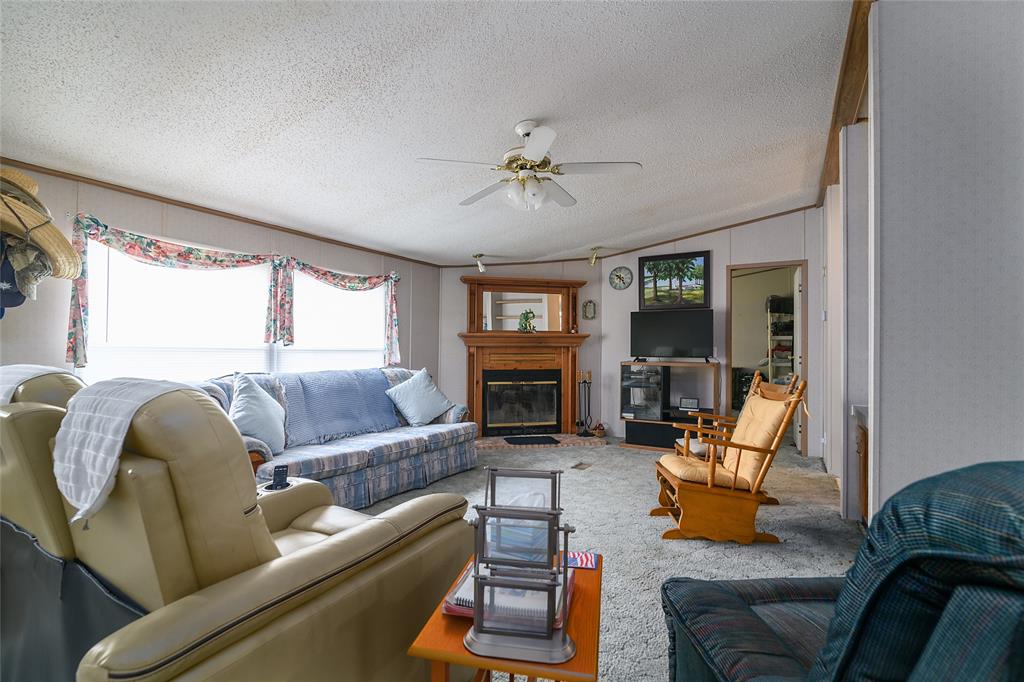 122 Grice Road Ringgold, LA 71068 - Photo 9 of 26 Living area featuring a fireplace with a wood-finish mantel, ceiling fan, and carpeted flooring