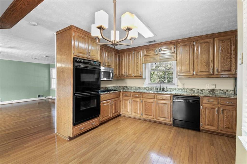 2678 North Bogan Road Northeast Buford, GA 30519 - Photo 48 of 52 a kitchen with granite countertop wooden floors stainless steel appliances and sink