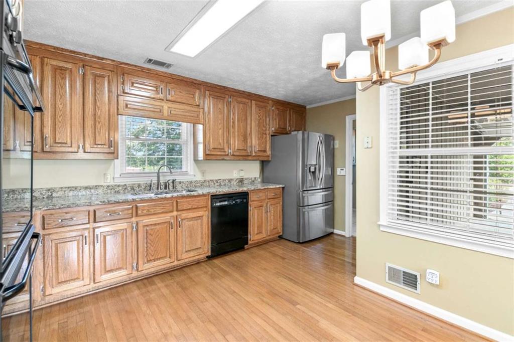 2678 North Bogan Road Northeast Buford, GA 30519 - Photo 49 of 52 a kitchen with stainless steel appliances granite countertop a refrigerator a sink dishwasher a stove and a dining table with wooden floor