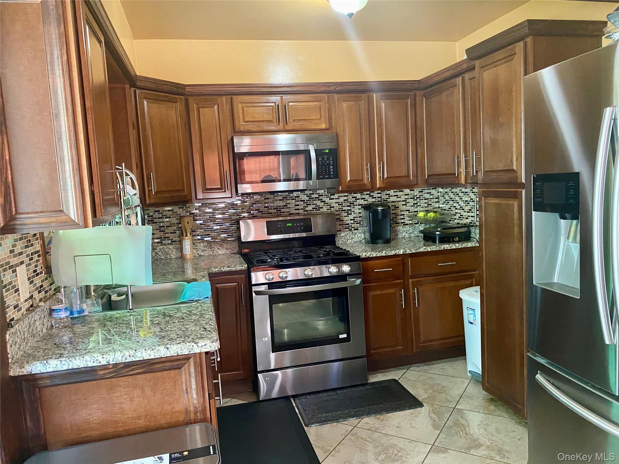 204 Beech Street Valley Stream, NY 11580 - Photo 4 of 18 a kitchen with stainless steel appliances granite countertop a stove a microwave and a sink
