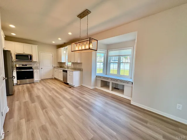 a open kitchen with granite countertop a stove top oven a sink dishwasher a dining table and chairs with wooden floor