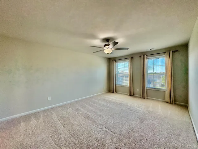 a view of an empty room with a chandelier fan