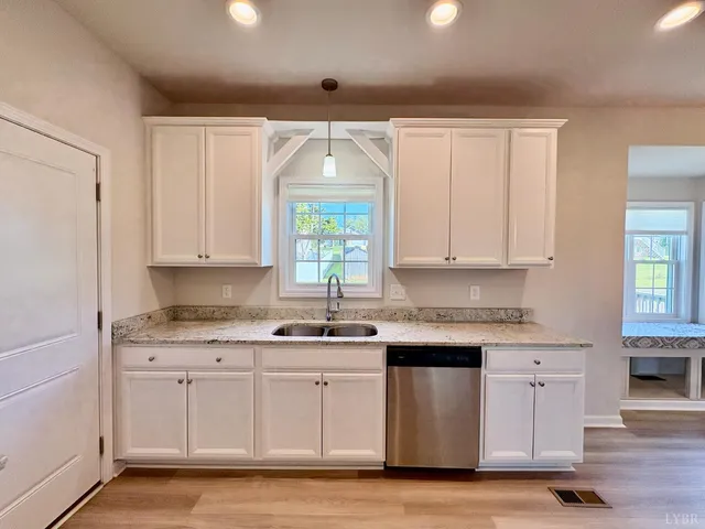a kitchen with granite countertop white cabinets stainless steel appliances a sink and a window