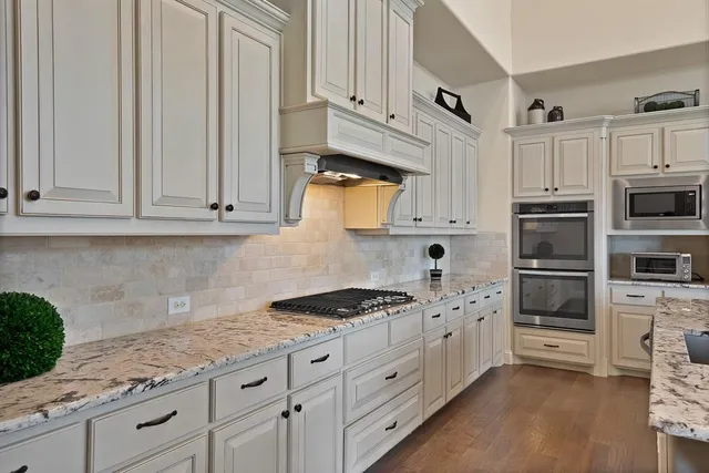a kitchen with granite countertop white cabinets and stainless steel appliances