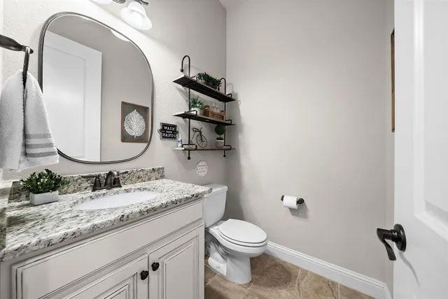 a bathroom with a granite countertop toilet sink and mirror
