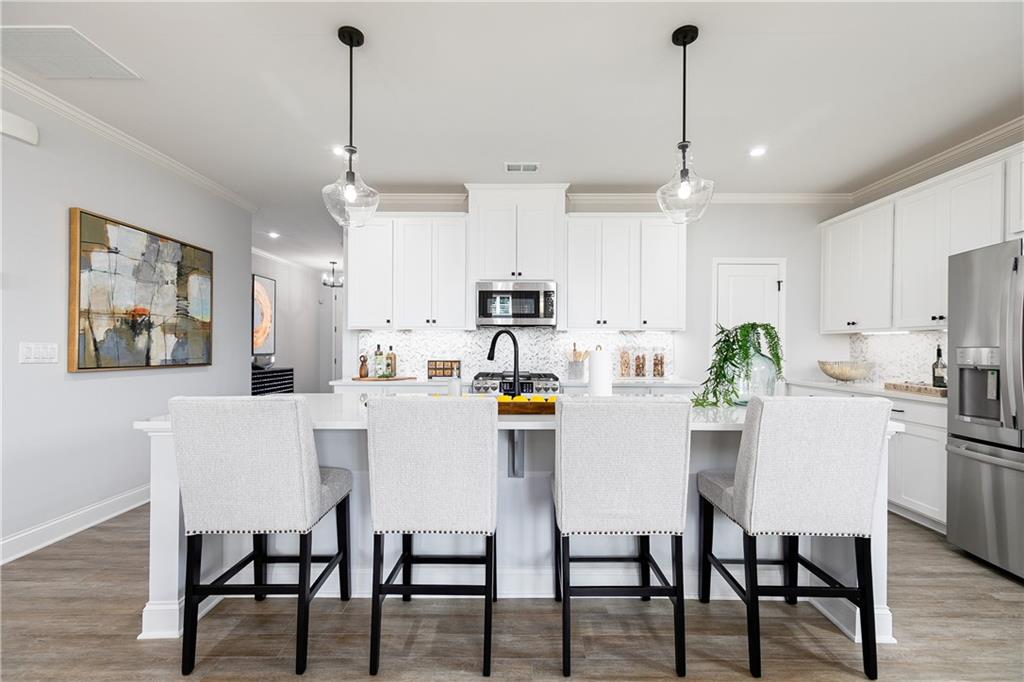 862 Leraes Way Loganville, GA 30052 - Photo 13 of 56 a kitchen with stainless steel appliances kitchen island granite countertop a dining table chairs and white cabinets
