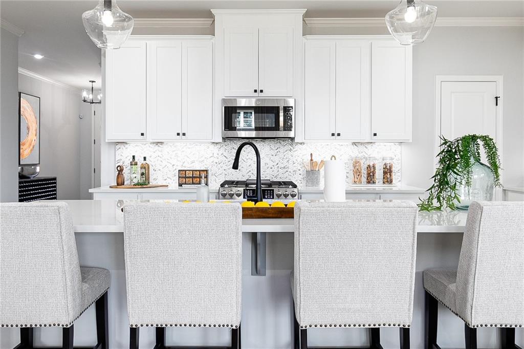 862 Leraes Way Loganville, GA 30052 - Photo 14 of 56 a kitchen with stainless steel appliances a white refrigerator a stove a sink a dining table and chairs with wooden floor