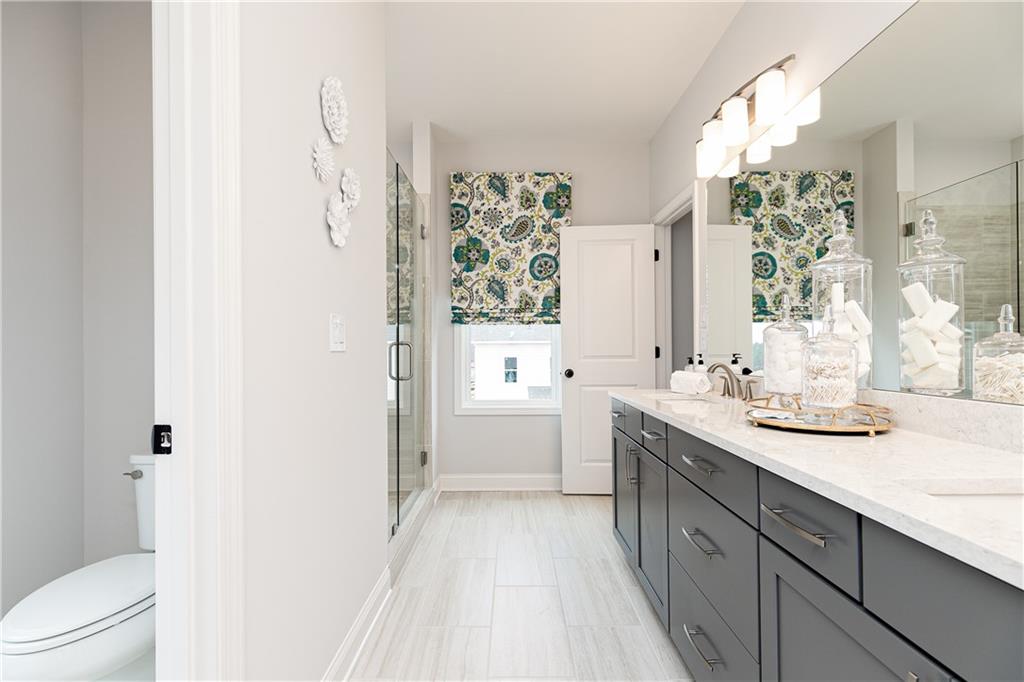862 Leraes Way Loganville, GA 30052 - Photo 29 of 56 a spacious bathroom with a granite countertop sink a toilet and shower curtain