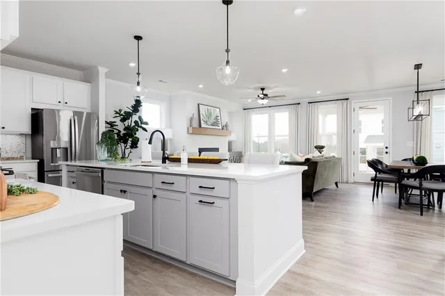 a kitchen with kitchen island a white counter top space a sink stainless steel appliances and cabinets