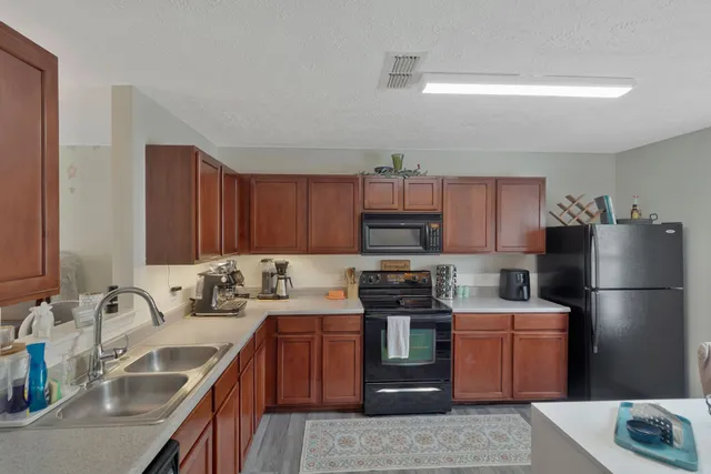 a kitchen with stainless steel appliances granite countertop a sink stove refrigerator and cabinets