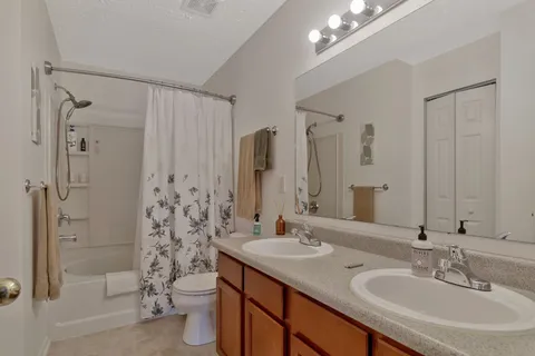 a bathroom with double vanity sinks a toilet a shower and a mirror