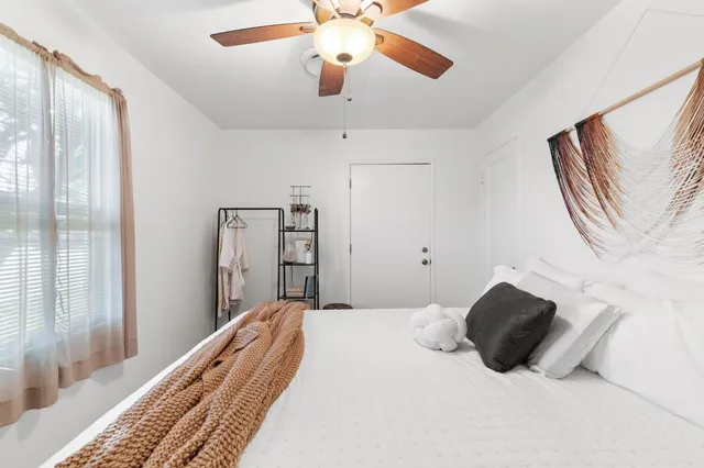 a bedroom with a bed lamp and a large window