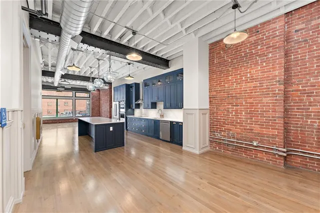a kitchen with stainless steel appliances granite countertop a sink a stove and a wooden floors
