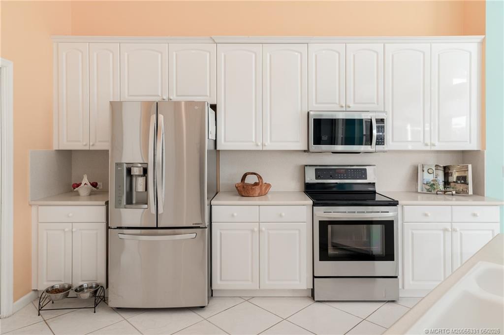 2216 Southeast Stonehaven Road Port St. Lucie, FL 34952 - Photo 14 of 67 a kitchen with white cabinets and stainless steel appliances