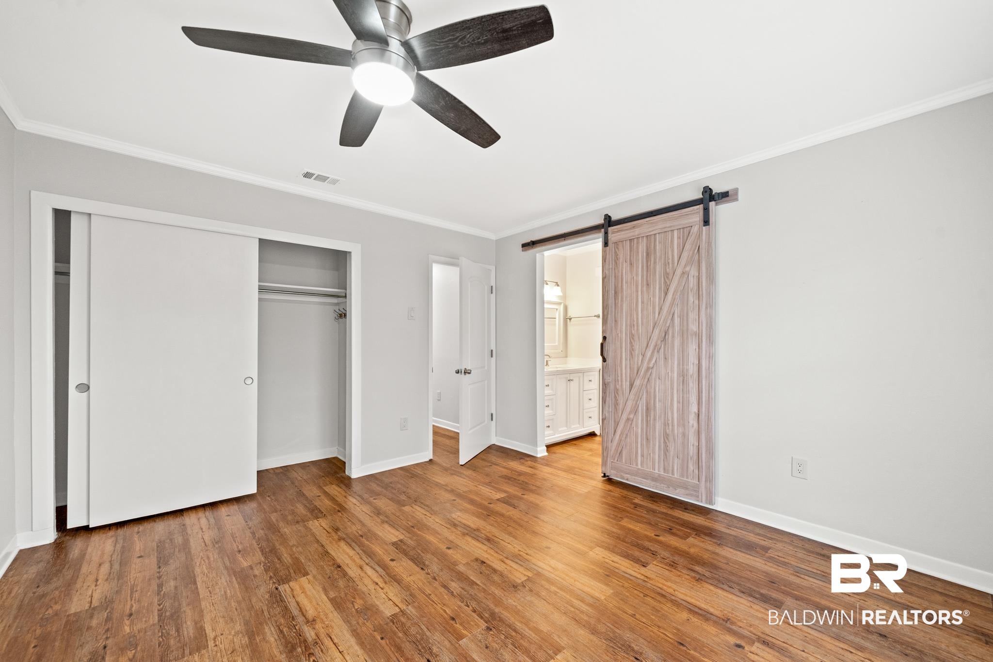 2901 Grant Street, Unit 802 Mobile, AL 36606 - Photo 19 of 37 Unfurnished bedroom featuring a barn door, ceiling fan, wood-type flooring, a closet, and ensuite bath