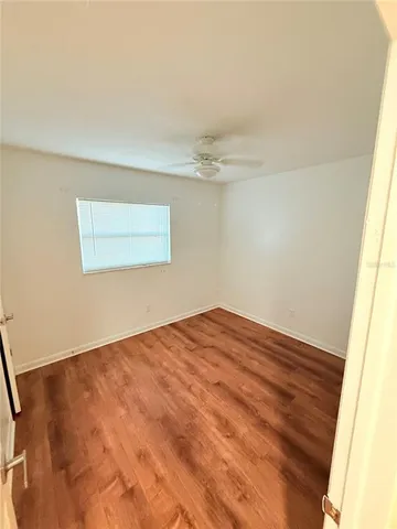 a view of empty room with wooden floor and fan