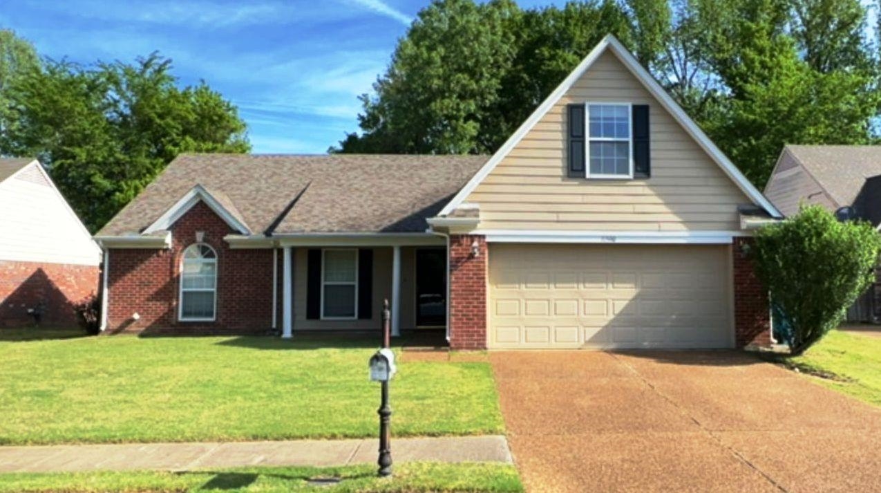 Traditional home with a front lawn, concrete driveway, covered porch, and brick siding