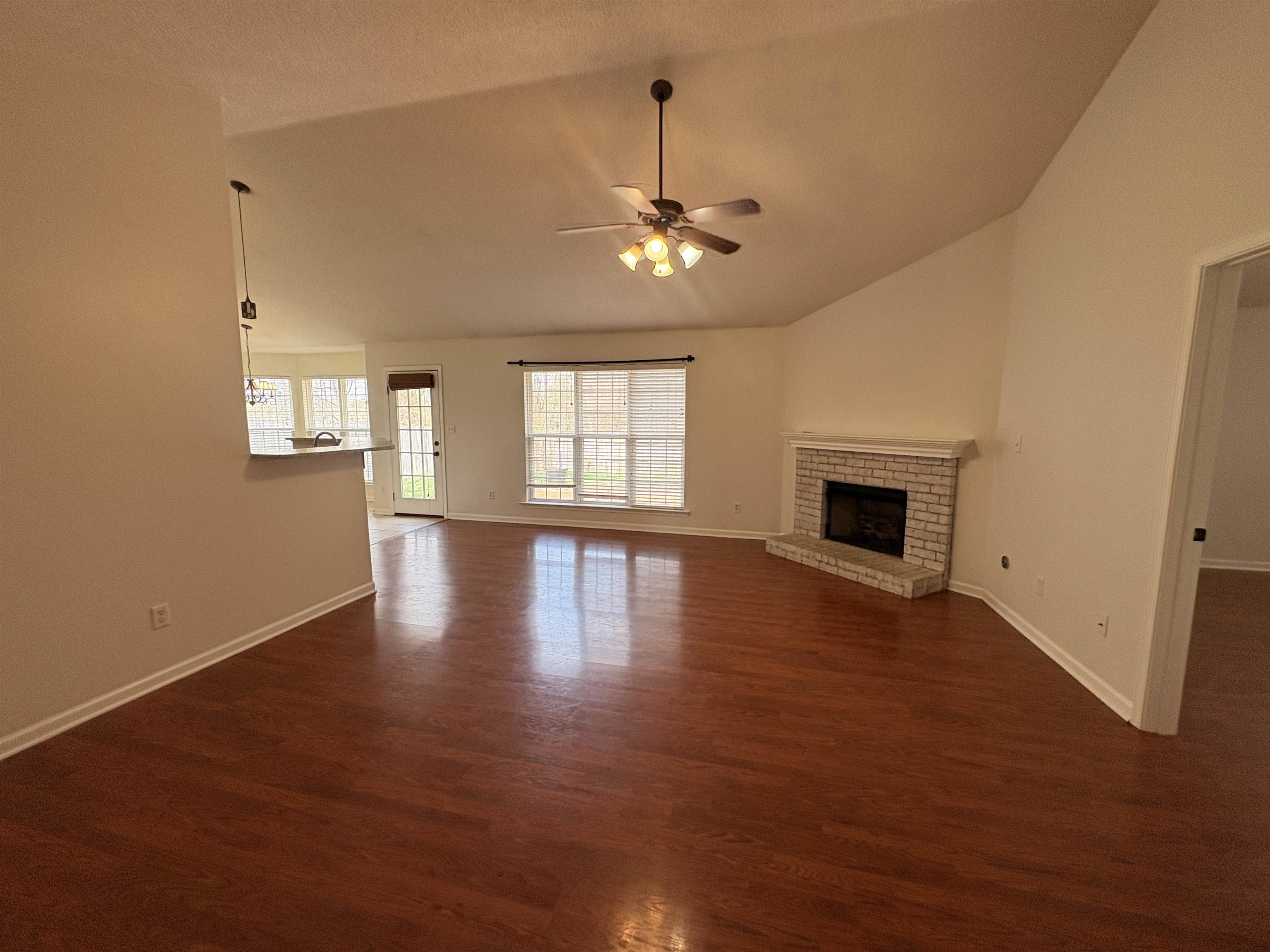 11590 Milton Ridge Cove Arlington, TN 38002 - Photo 3 of 24 Unfurnished living room featuring ceiling fan, dark wood finished floors, a fireplace, and vaulted ceiling