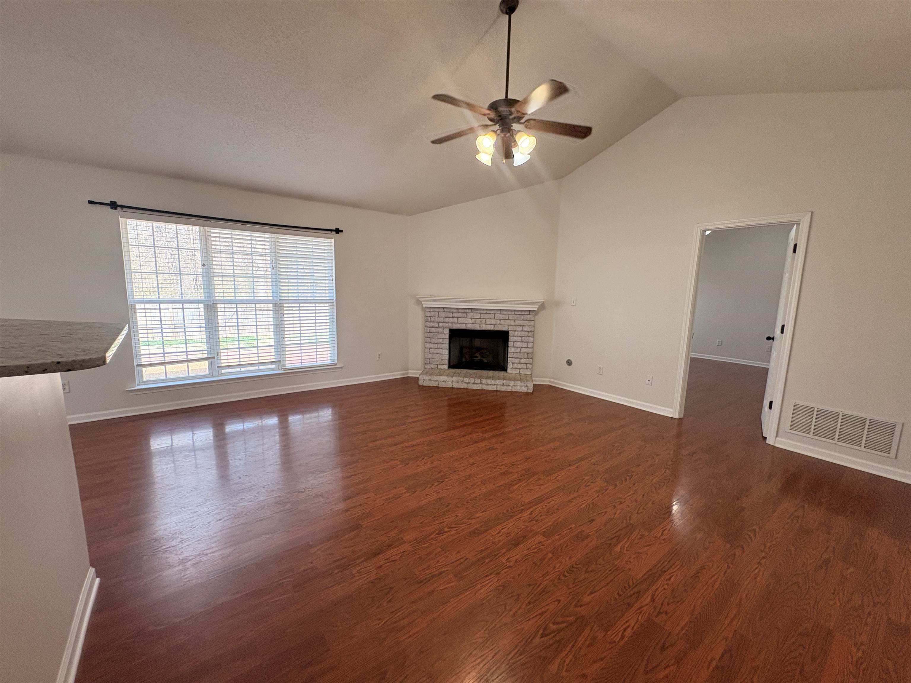 11590 Milton Ridge Cove Arlington, TN 38002 - Photo 5 of 24 Unfurnished living room with dark wood-style flooring, ceiling fan, and a brick fireplace