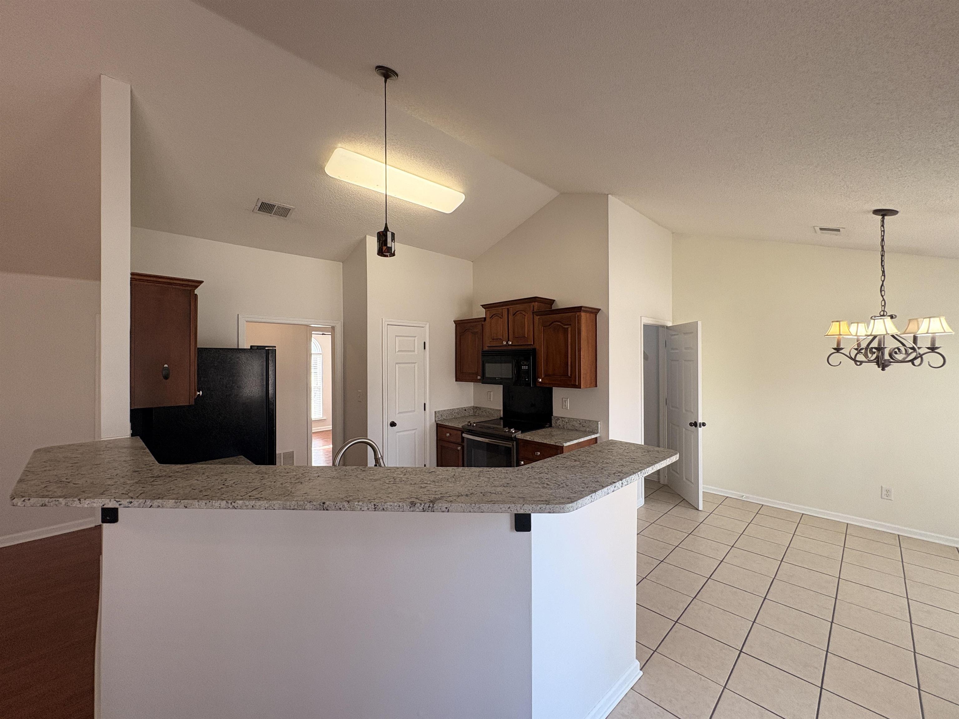 11590 Milton Ridge Cove Arlington, TN 38002 - Photo 6 of 24 Kitchen featuring black appliances, a kitchen bar, a chandelier, vaulted ceiling, and light tile patterned floors