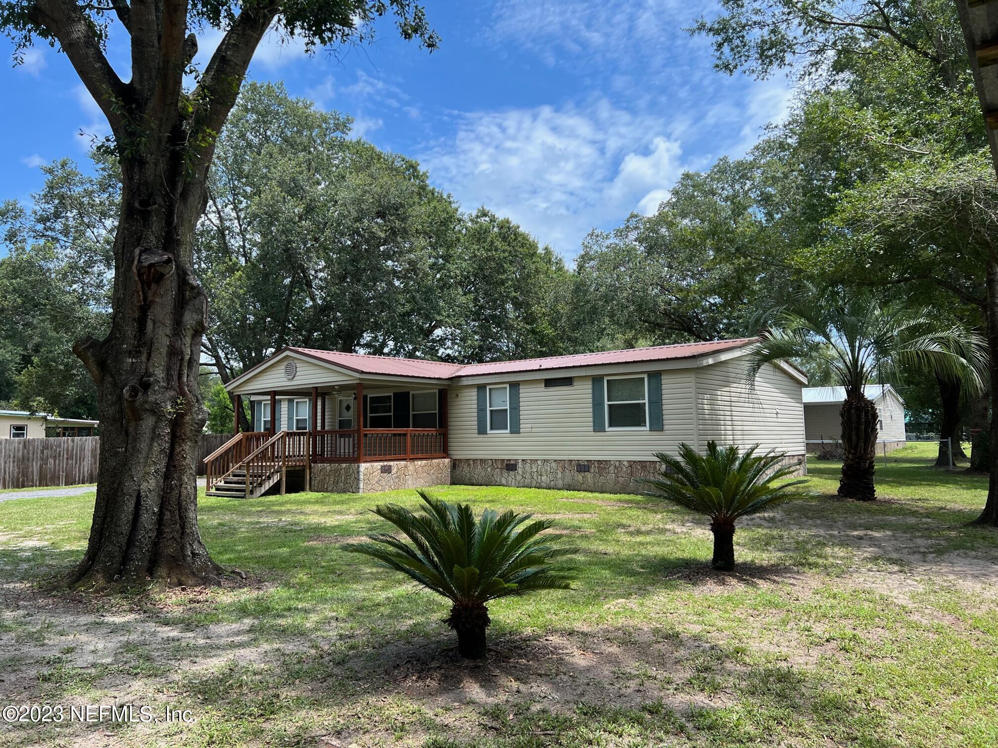 4097 South Wood Road Jacksonville, FL 32234 - Photo 2 of 7 a view of a house in front of a big yard with large trees and plants