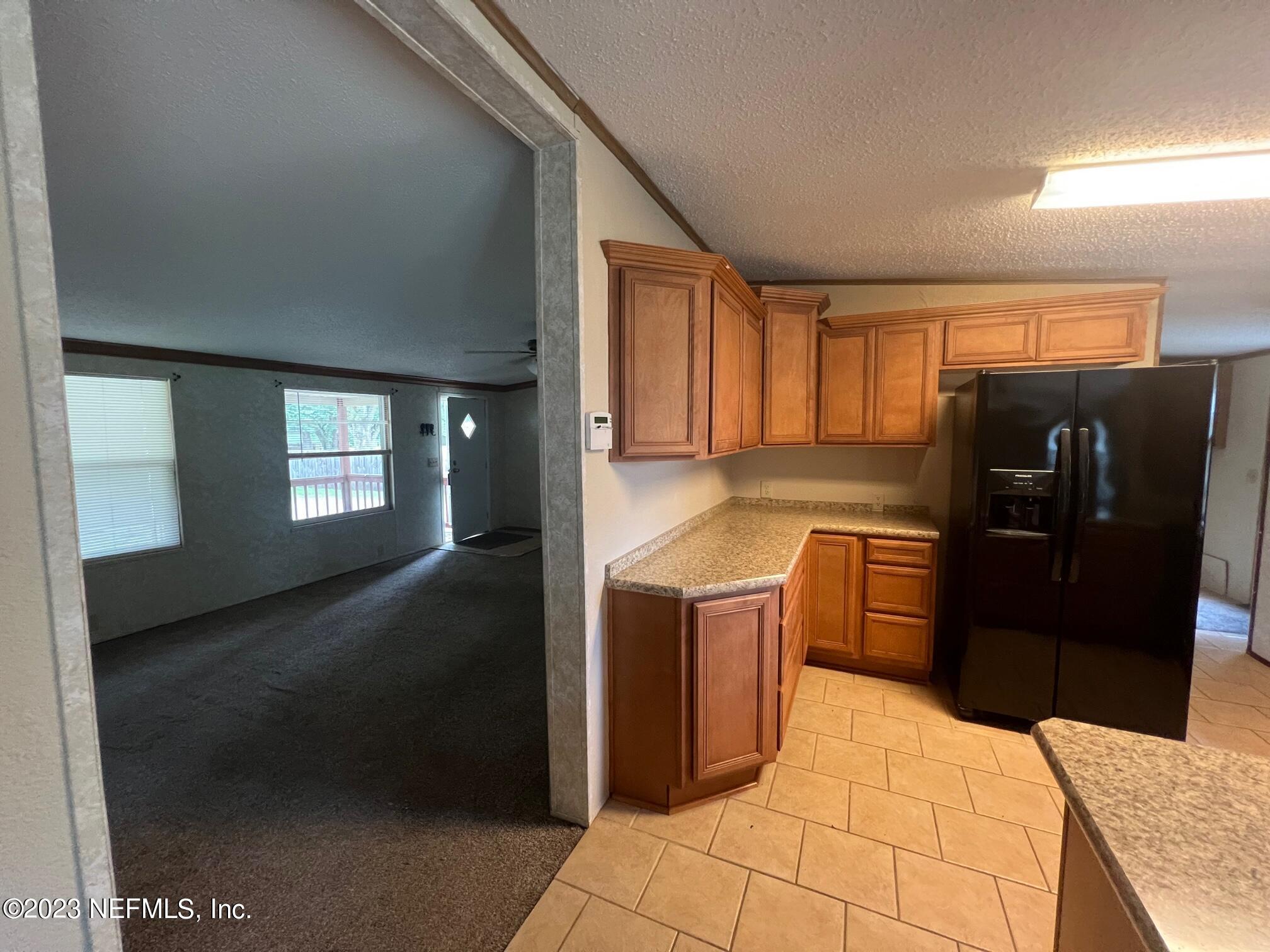 4097 South Wood Road Jacksonville, FL 32234 - Photo 4 of 7 a kitchen with stainless steel appliances kitchen island granite countertop a refrigerator a stove and a sink