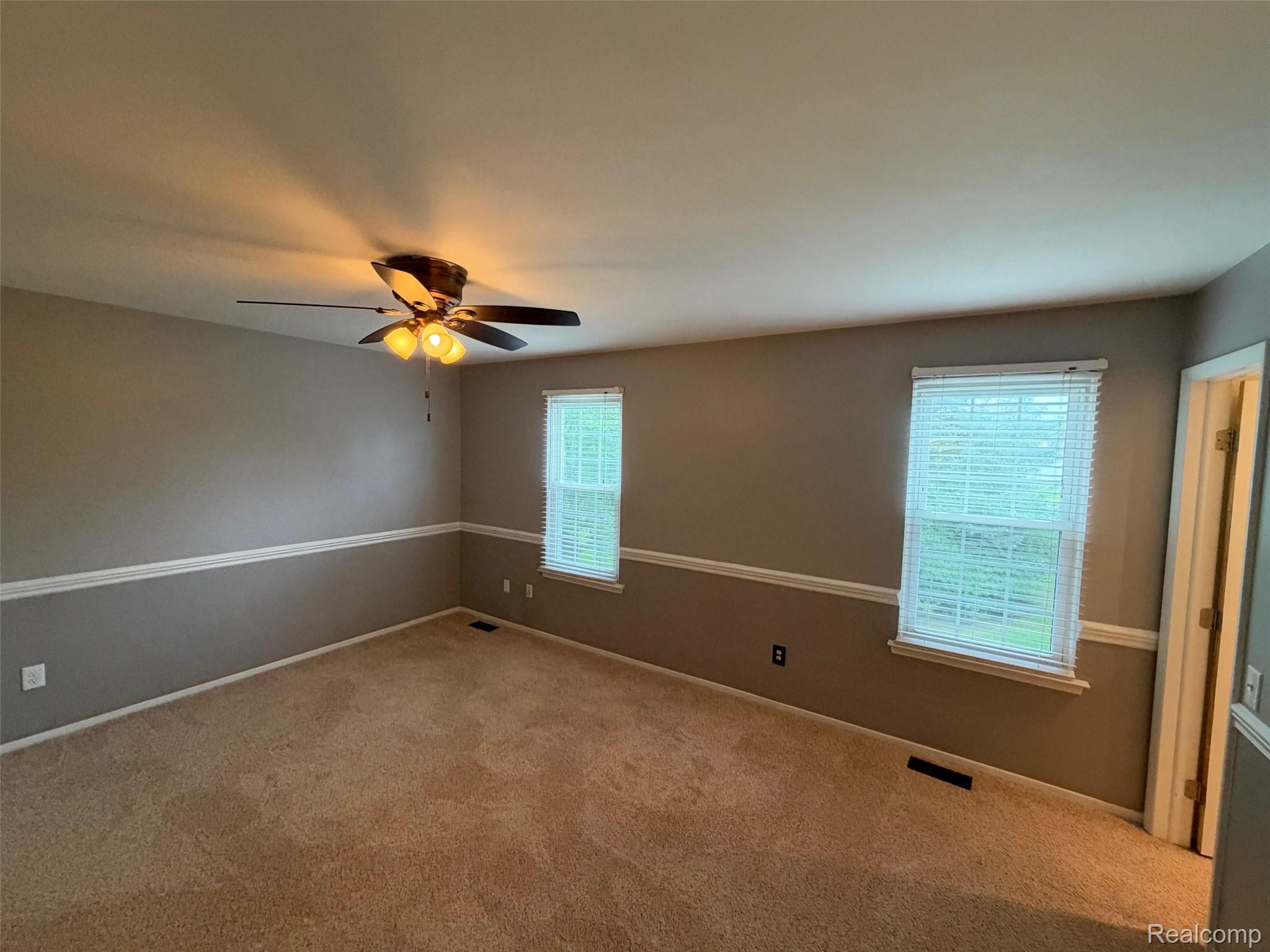 24525 Jamestowne Road Novi, MI 48375 - Photo 15 of 20 Carpeted room featuring a ceiling fan with integrated lighting, two windows with blinds, and two-tone painted walls with chair rail molding